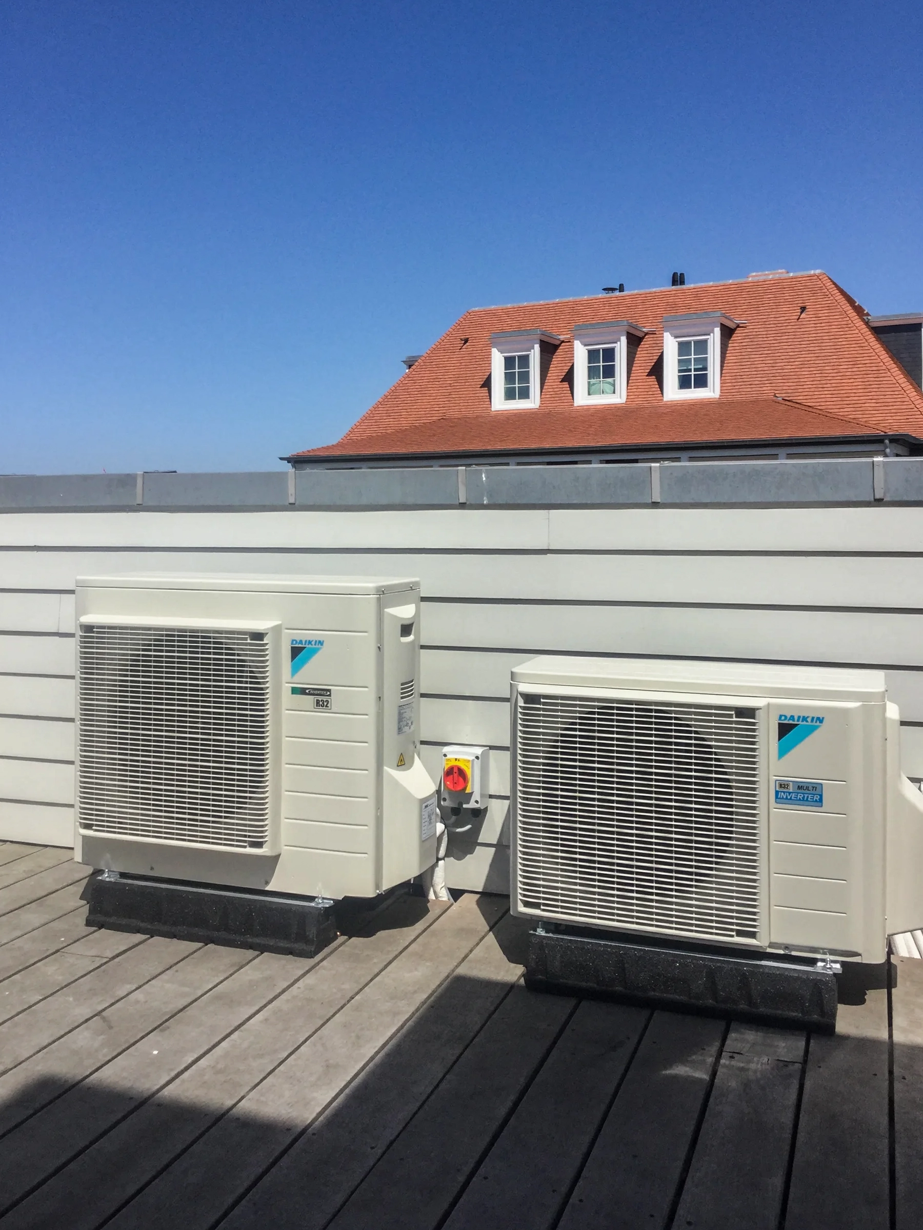 Twee buitenunits van een residentiële airco op een houten dakterras